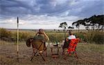 Kenya, Mara North Conservancy. A couple enjoy a sundowner in the Mara North Conservancy.