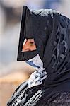 Oman, Ad Dakhiliyah Governorate, Nizwa. A black masked woman at the lively livestock market at Nizwa where local farmers sell goats and cattle. These masks usually denote a woman s Bedouin heritage.