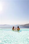 Couple in swimming-pool having cocktails