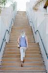 Blond woman walking up a staircase.