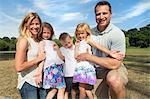 Family with three children in a park, posing for a picture.