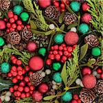 Christmas abstract background with red and green bauble decorations, holly, ivy, mistletoe, blue spruce fir and cedar cypress greenery.