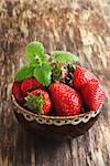 ripe strawberry and mint leaves in a bowl on wooden background. vegetables from his garden.health and diet food. selective focus