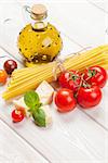 Italian food cooking ingredients. Pasta, tomatoes, basil on wooden table