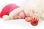 sleeping baby Santa Claus red hat and holding Christmas tree decoration