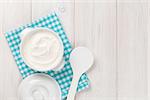 Sour cream in a bowl on wooden table. Top view with copy space