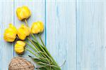 Yellow tulips over wooden table background with copy space