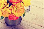 Colorful tulips bouquet in watering can on wooden table. Top view with copy space. Retro toned