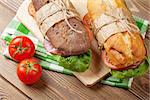 Two sandwiches with salad, ham, cheese and tomatoes on wooden table