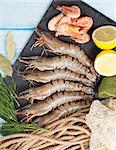 Fresh raw tiger prawns and fishing equipment on wooden table