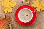 Autumn leaves and coffee cup over wood background