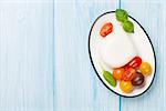Mozzarella, tomatoes and basil on wooden table. Top view with copy space