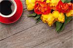 Colorful tulips bouquet and coffee cup on wooden table. Top view with copy space