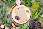 Fresh garden herbs and notepad for your recipes on wooden table