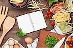 Pasta cooking ingredients and utensils on wooden table. Top view with notepad for copy space