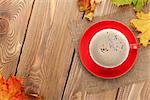 Autumn leaves and coffee cup over wood background with copy space