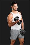 Portrait of handsome young man lifting weights, isolated over a gray background