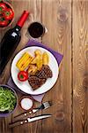 Steak with grilled potato, corn, salad and red wine on wooden table. Top view with copy space