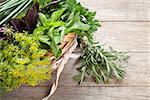 Fresh garden herbs in basket on wooden table. Top view