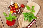 Fresh tomato juice smoothie with basil on wooden table. Top view