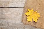 Autumn maple leaves over burlap texture background with copy space