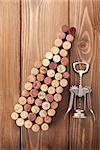 Wine bottle shaped corks and corkscrew over rustic wooden table background. Top view