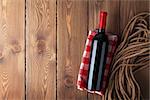 Red wine bottle over rustic wooden table background with copy space