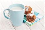 Cup of milk and cakes on white wooden table