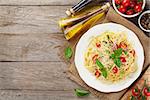 Spaghetti pasta with tomatoes and parsley on wooden table. Top view with copy space