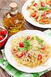 Spaghetti and penne pasta with tomatoes and parsley on wooden table