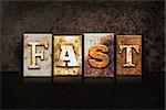 The word "FAST" written in rusty metal letterpress type on a dark textured grunge background.