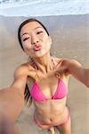 Asian young woman or girl in bikini, taking vacation selfie photograph at the beach