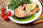 Grilled salmon and salad on wooden table