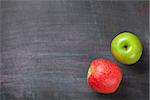 Green and red apples on blackboard or chalkboard background. Top view with copy space