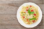 Spaghetti pasta with tomatoes and basil on wooden table. Top view with copy space