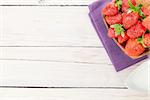 Fresh ripe strawberry in bowl and milk over wooden table background. Top view with copy space