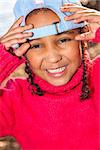 Portrait photograph of a beautiful young smiling happy mixed race interracial African American girl wearing light blue baseball cap