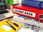 Client Base - Red Office Folder on Background of Working Table with Stationery, Laptop and Reports. Business Concept on Blurred Background. Toned Image.