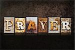 The word "PRAYER" written in rusty metal letterpress type on a dark textured grunge background.