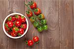 Cherry tomatoes bowl on wooden table. Top view with copy space