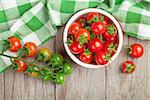 Cherry tomatoes bowl on wooden table. Top view