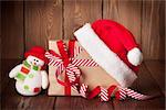 Christmas gift box with santa hat and snowman toy on wooden table