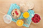 Healthy breakfast with muesli, berries and orange juice. On wooden table