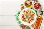 Colorful penne pasta and white wine on wooden table. Top view with copy space