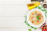 Spaghetti pasta with tomatoes and basil on wooden table. Top view with copy space