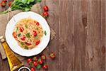 Spaghetti pasta with tomatoes and parsley on wooden table. Top view with copy space