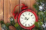 Christmas clock and snow fir tree over wooden background