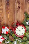 Christmas wooden background with clock, snow fir tree and gift boxes