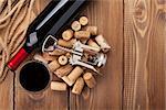 Glass of red wine, bottle and corkscrew on rustic wooden table. Top view with copy space