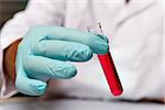 Closeup hand of chemist with a red liquid